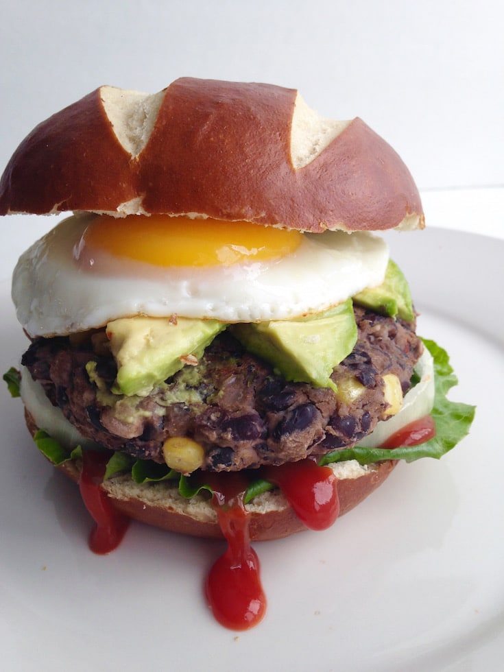 A black bean burger with avocado and egg on top.