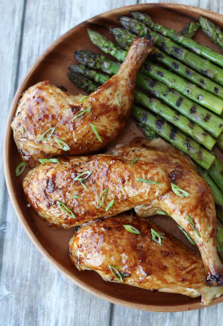 A plate with sliced chicken with grilled asparagus.