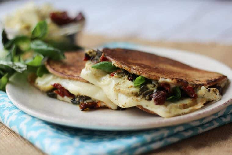grilled cheese with artichoke and basil on a white plate