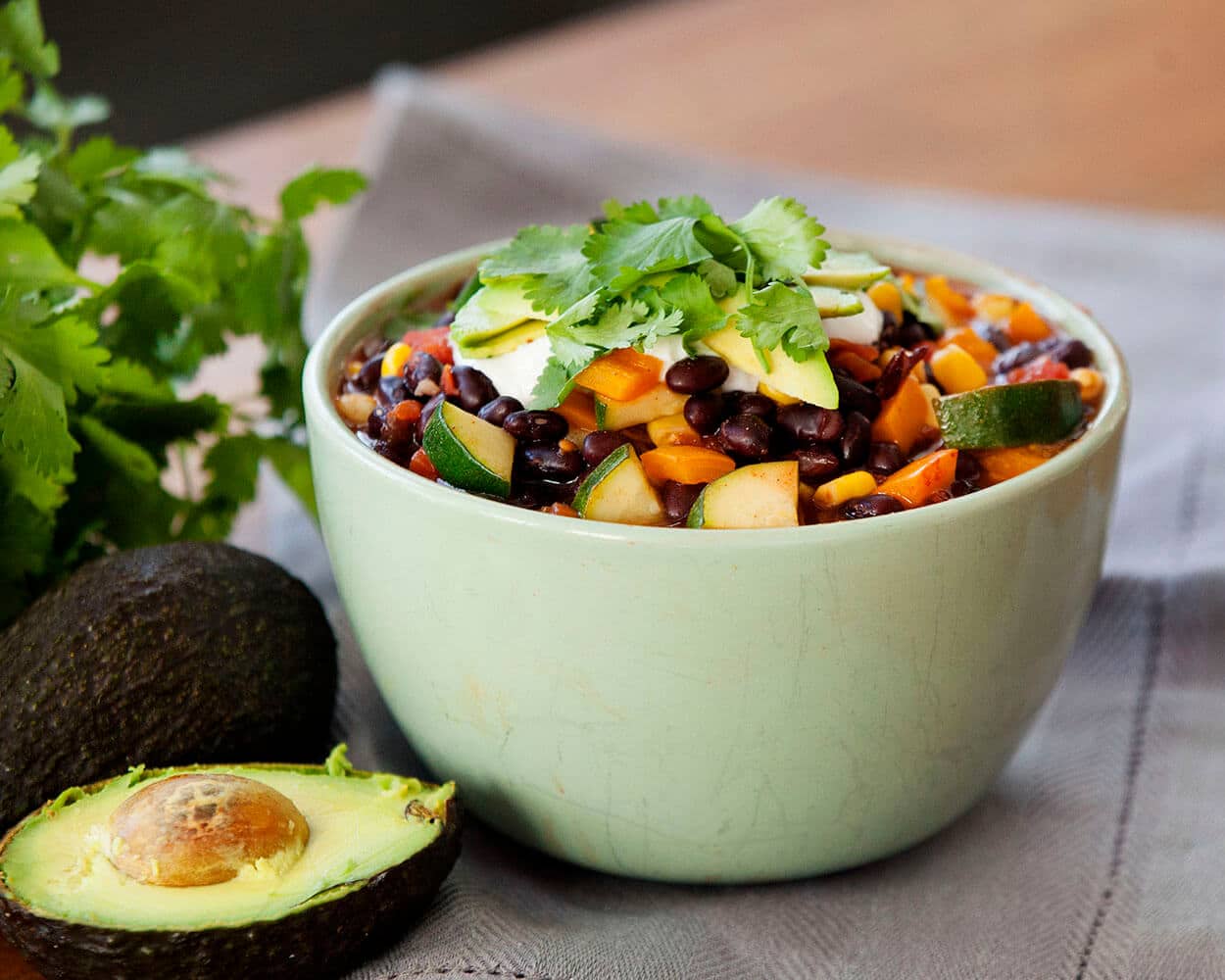 A green bowl of soup with beans.