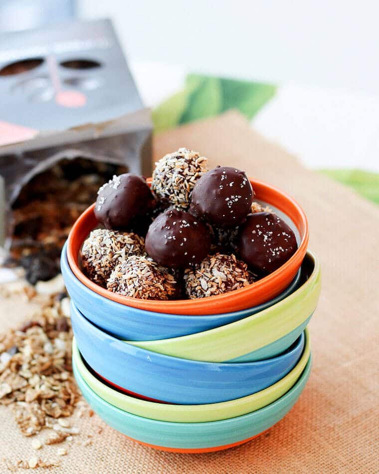 A stack of colorful bowls with the top one filled with vegan truffles.