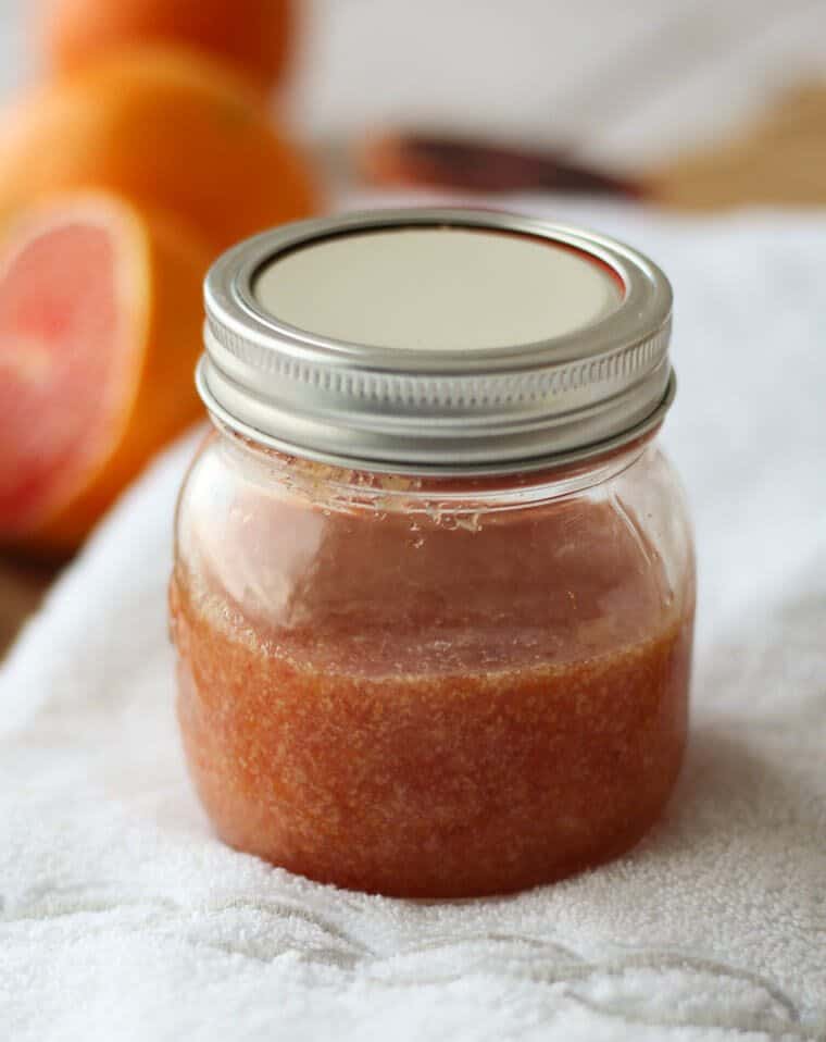 A mason jar with blood orange ginger body scrub.