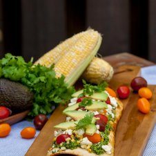 A tasty corn cilantro pesto grilled pizza with pesto, corn, and feta.