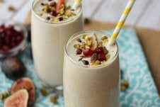 Two glasses of pistachio smoothies with fig toppings and paper straws.