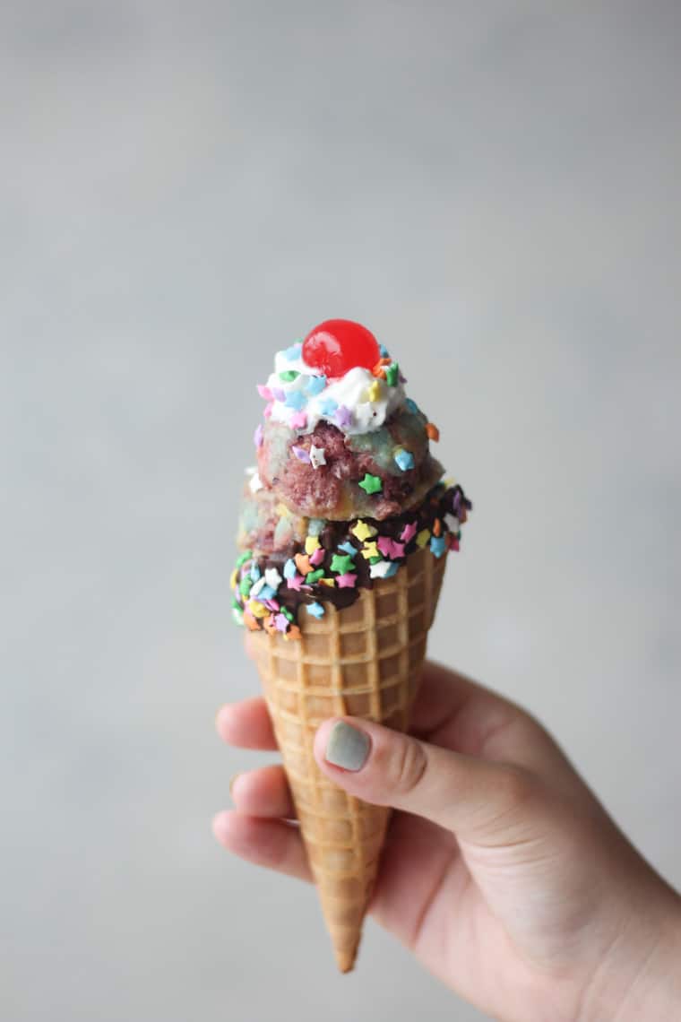 Hand holding a cone of unicorn nice cream.