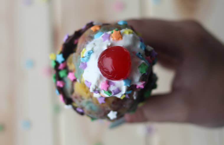 Unicorn nice cream in a cone topped with whip cream and cherry.