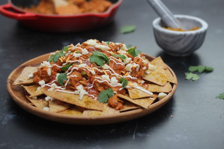 A close up of a plate of butter chicken nachos.