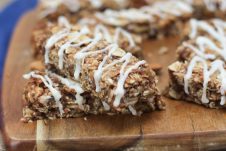 A close up image of multiple cinnamon bun granola bars on a brown cutting board.
