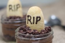 A close up of a Halloween graveyard mousse with an edible gravestone saying RIP in chocolate with a second one in the background.