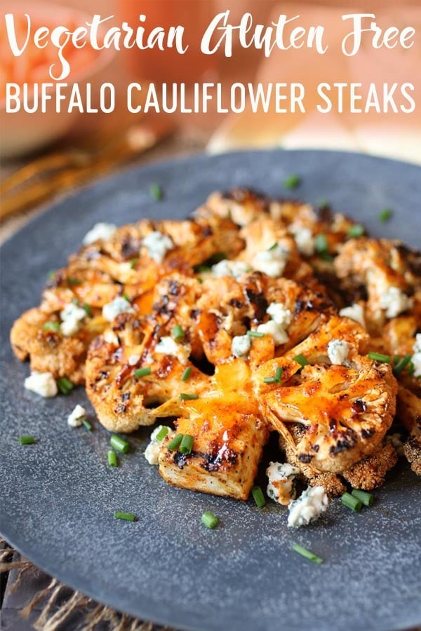 Buffalo cauliflower steaks on a grey plate topped with blue cheese and chives.