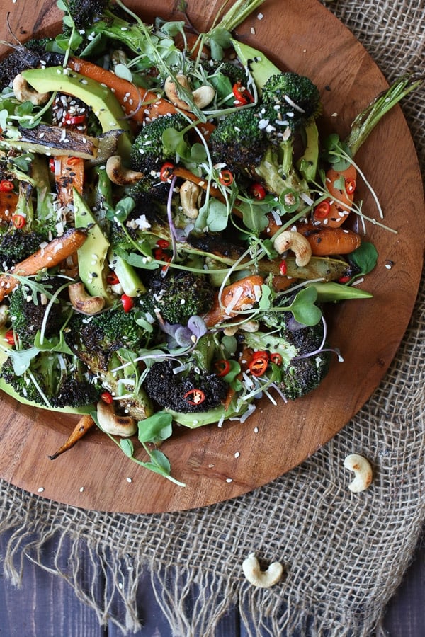 Grilled broccoli and carrot salad on a wooden plate.