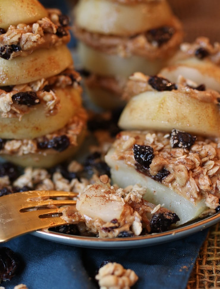 close up of a fork taking a bite from gluten free poached pears layered with gluten free granola on a grey plate