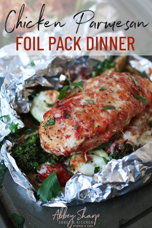 chicken parmesan dinner in foil pack on a bed of vegetables and topped with parsley