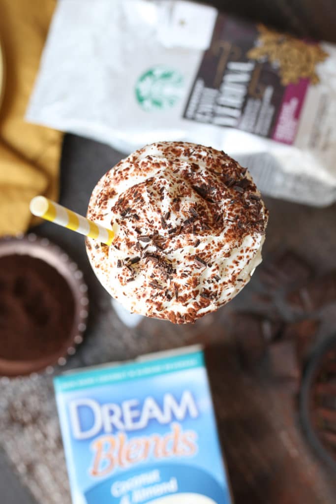 Birds eye view of tiramisu milkshake topped with whip cream next to a bag of Starbucks coffee.