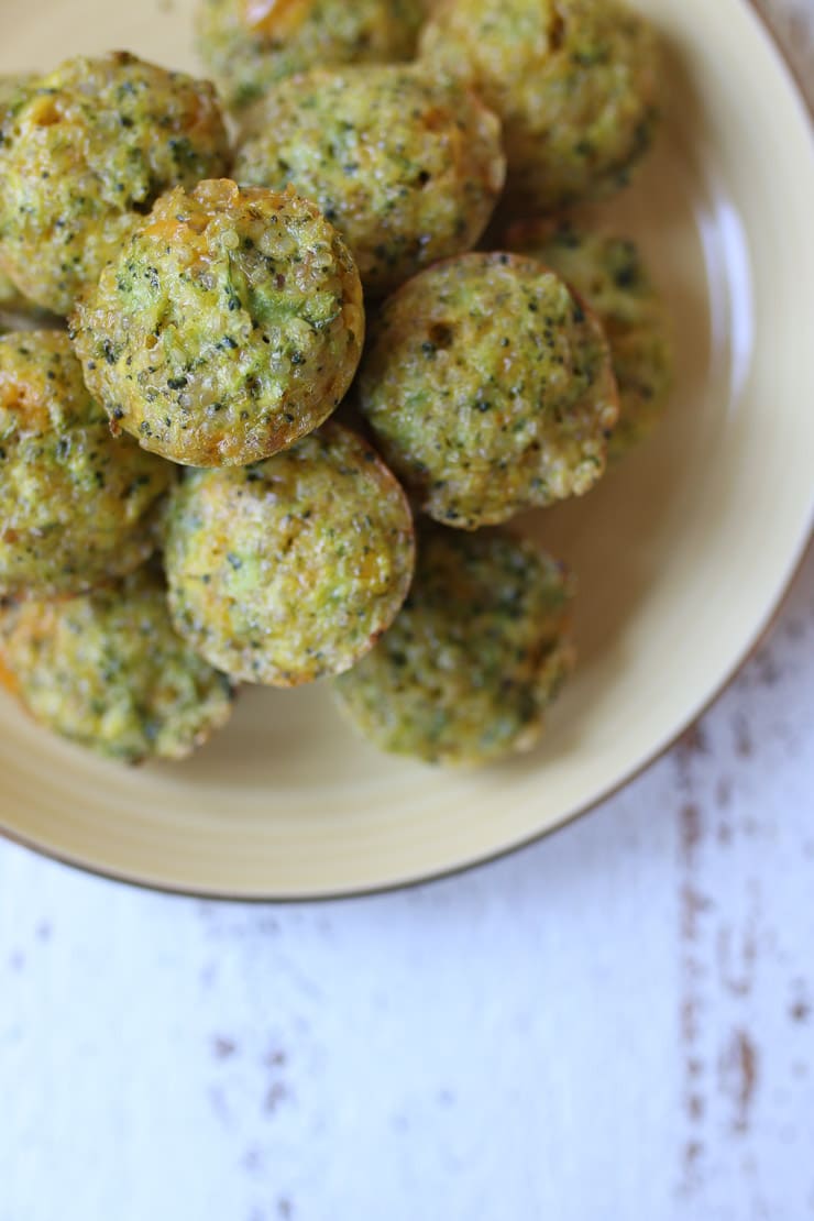 Pile of mini broccoli and cheese egg bites on a yellow plate.