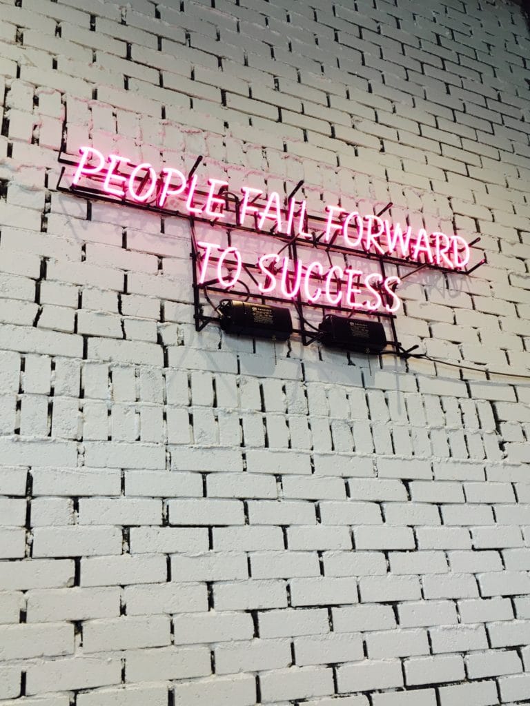 Neon sign on a white brick wall.
