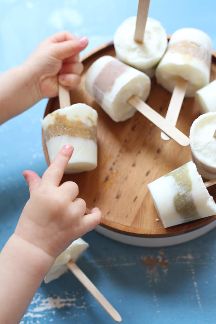 Baby holding baby popsicles.