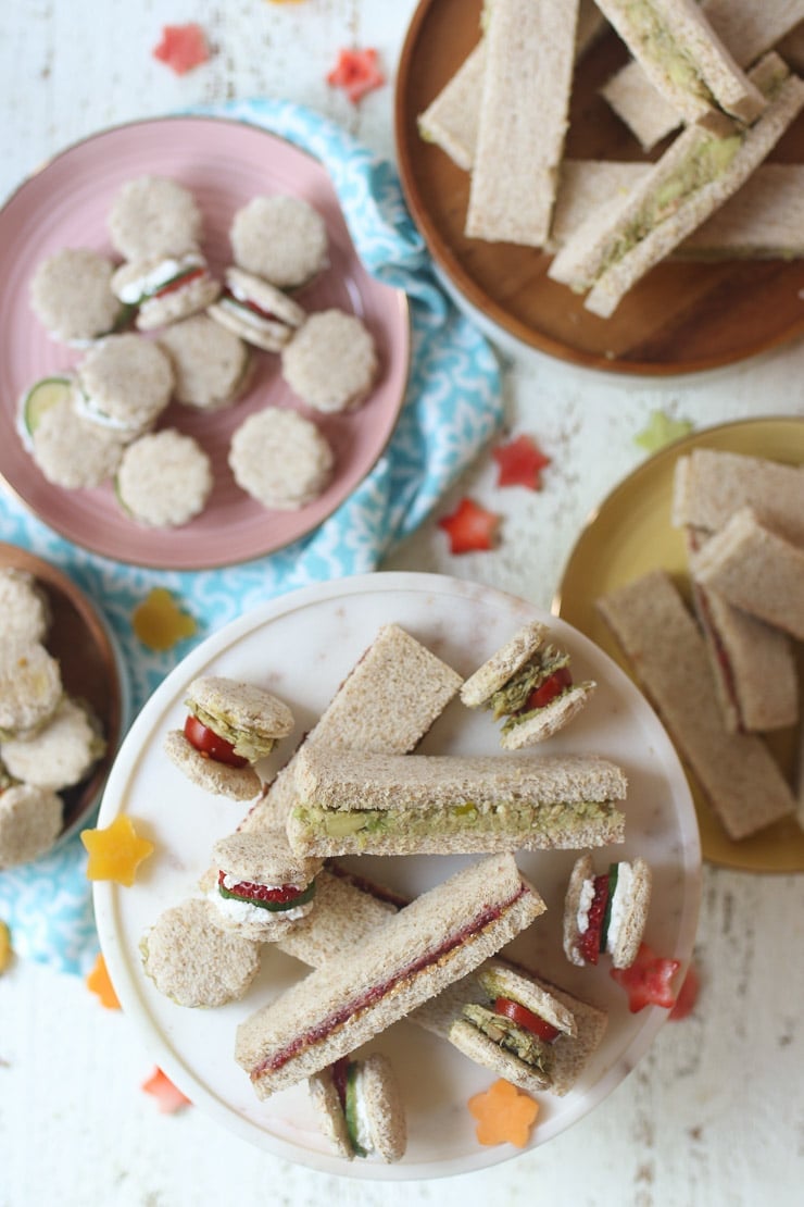 Finger sandwiches on several plates.