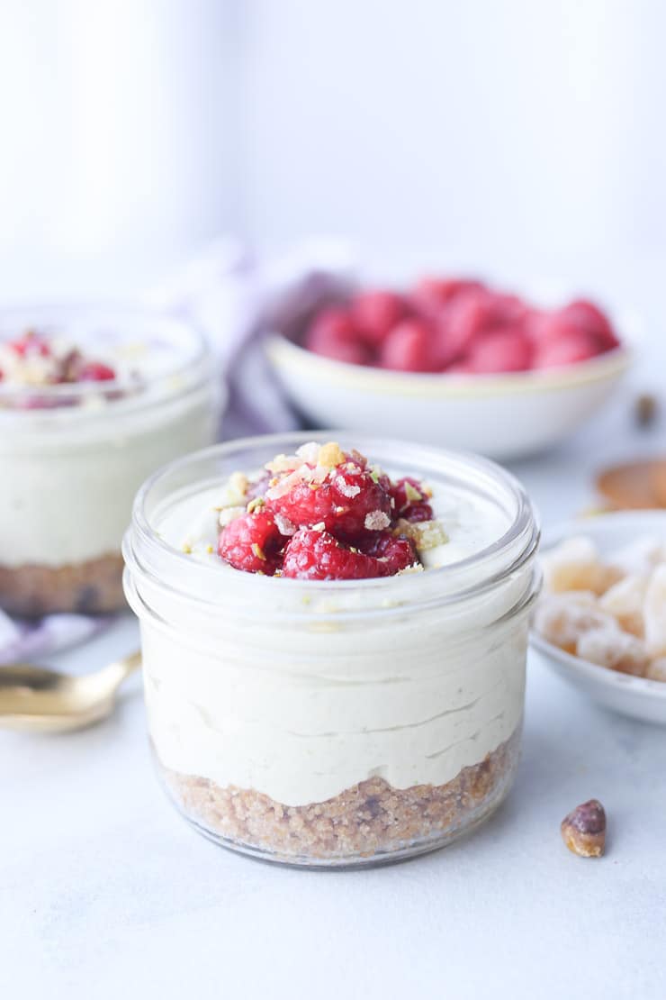 Matcha cheesecake parfait in a glass mason jar topped with berries.