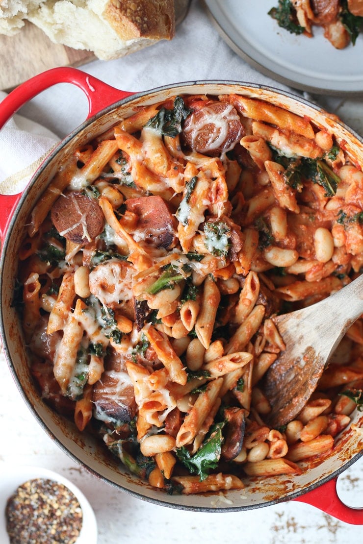 Pasta bake in red casserole dish with wooden spoon 