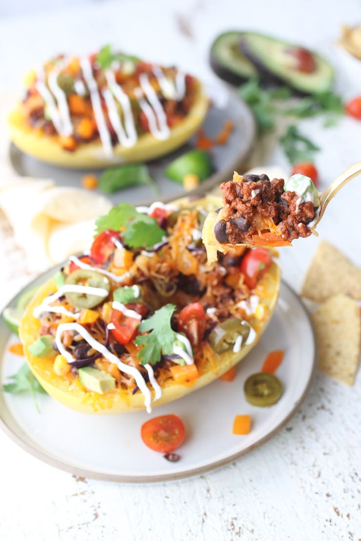 full shot vegan and gluten free spaghetti squash burrito bowl served on a white plate garnished with fresh japalenos and cilantro