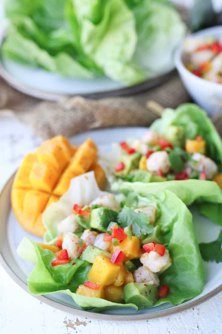 Mango avocado salad on a white plate garnished with shrimp.