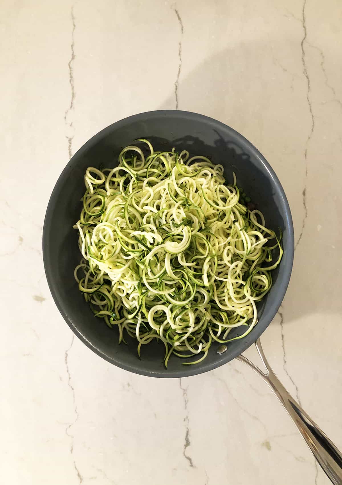 Zucchini zoodles in a frying pan.
