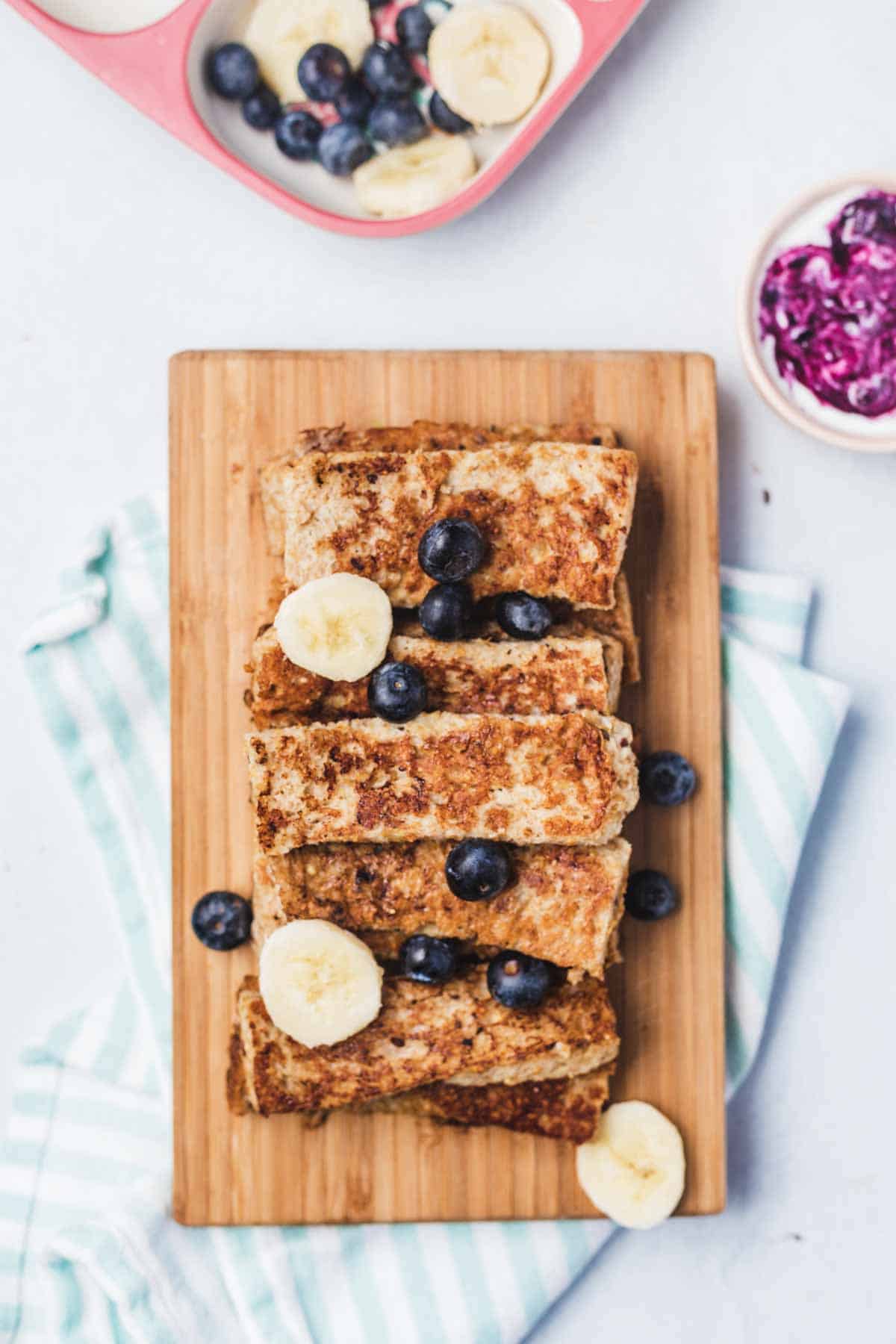 Overhead view of a serving board with a stack of French toast sticks.