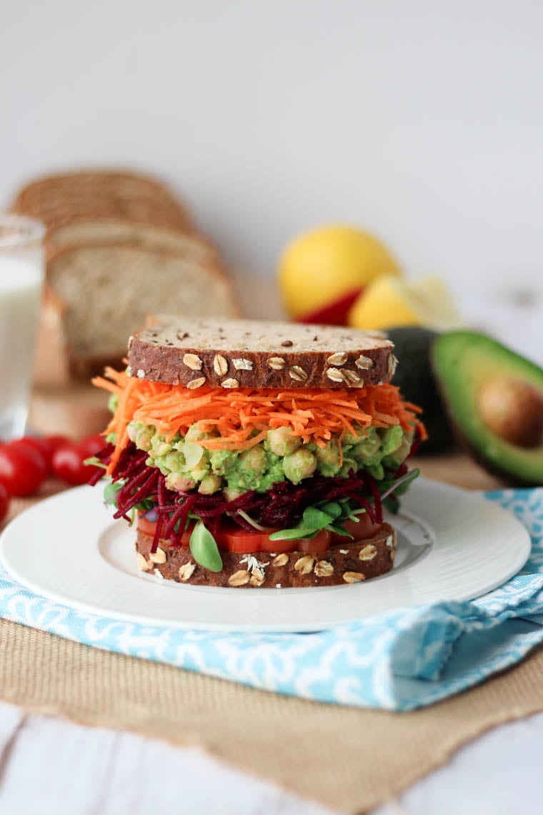 Close up of vegan chickpea salad sandwich on a white plate.