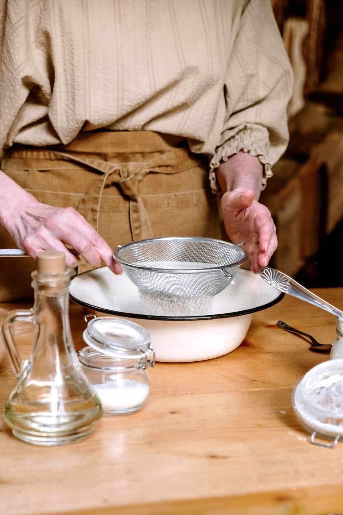 Woman sifting flour into  a bowl.