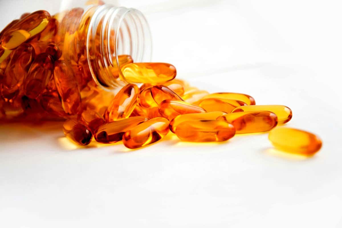 Spilled jar of clear orange dietary supplements.
