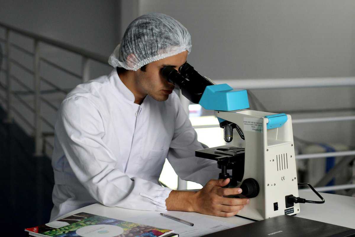 Man in a food manufacturing facility looking in a microscope.