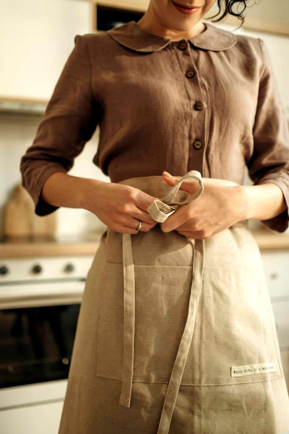Trad wife influencer tying on an apron.