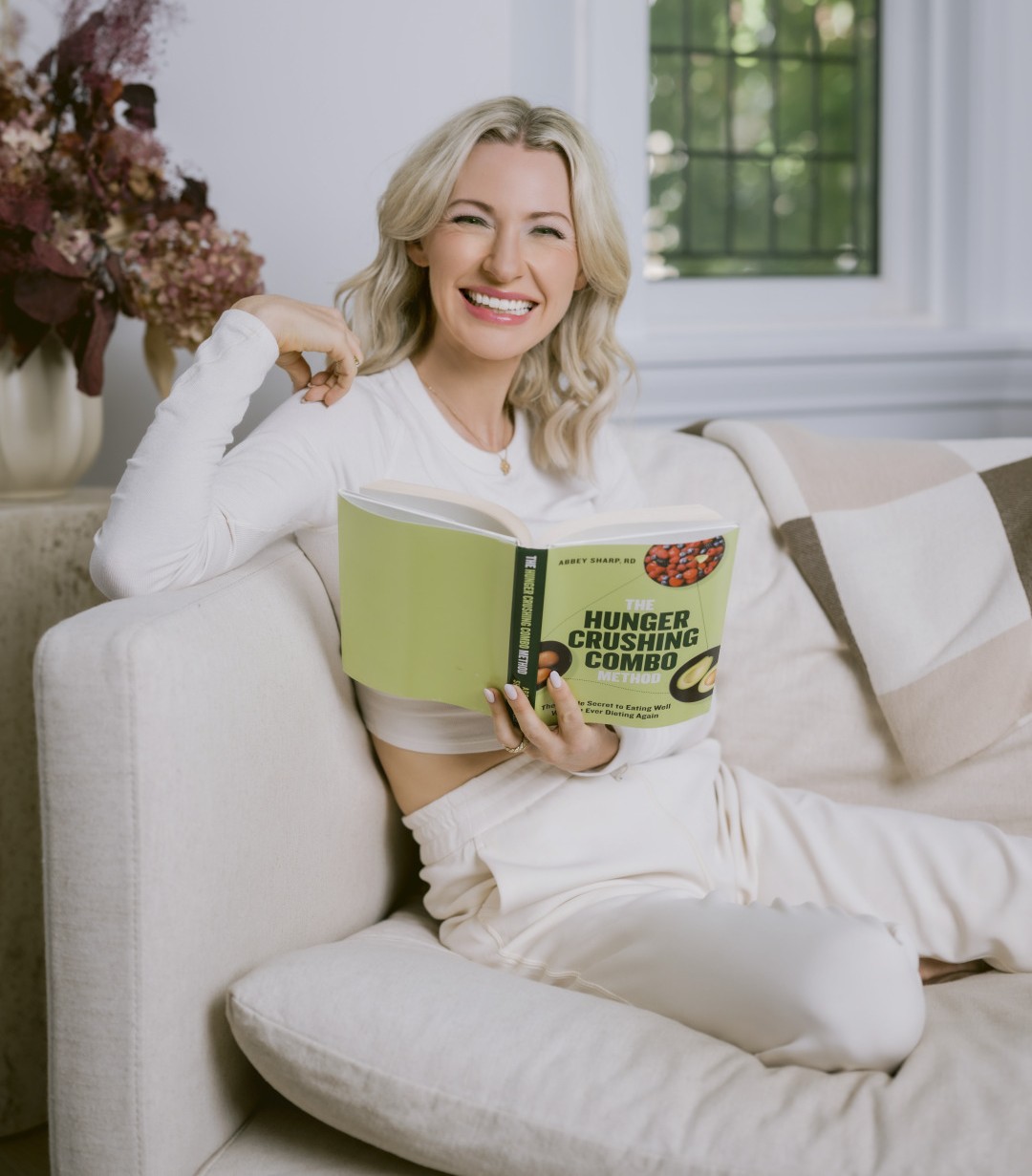 Abbey Sharp Sitting on Couch with Hunger Crushing Combo Book